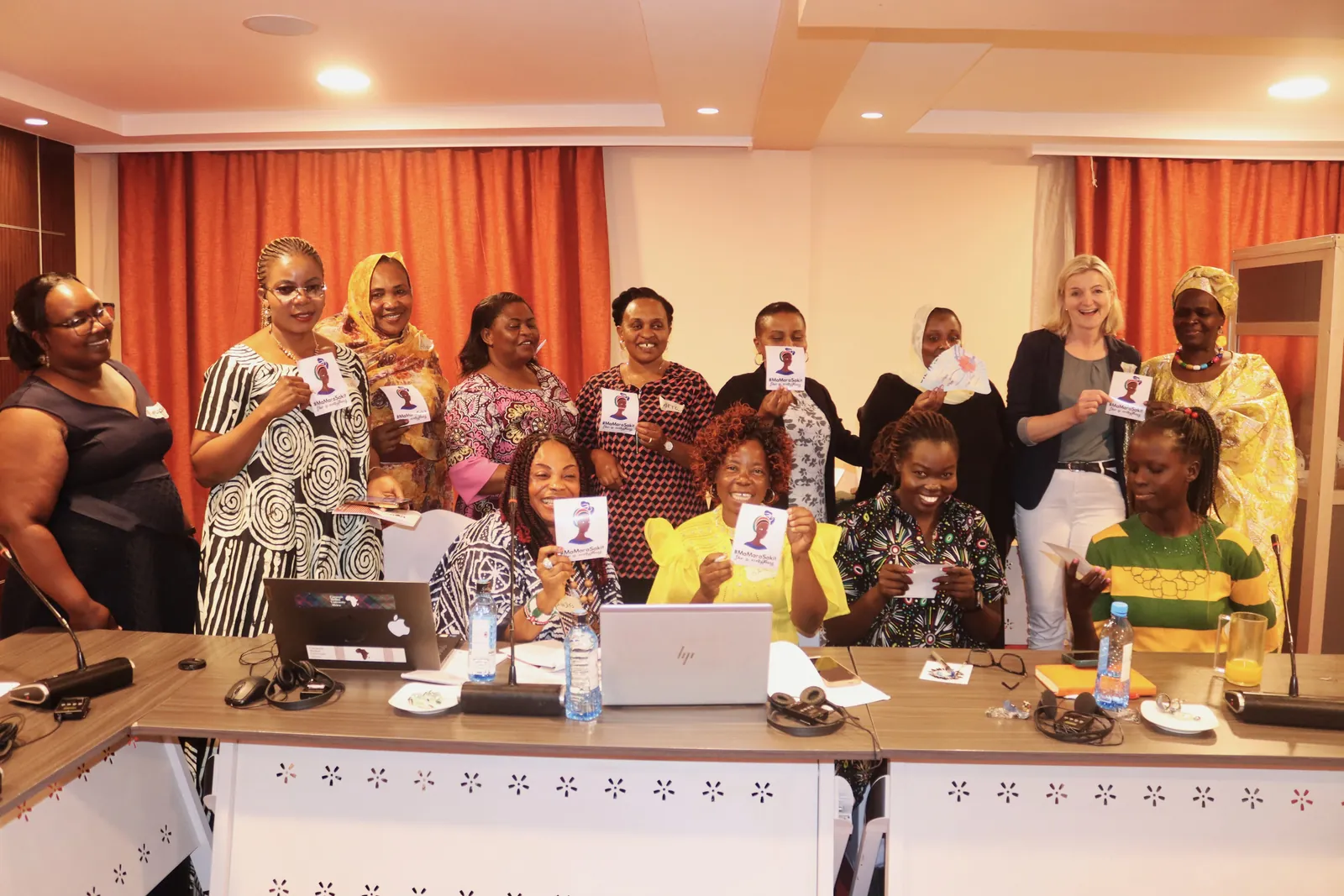 Refugee women leaders holding up cards around a conference table at the first ARWNET Summit