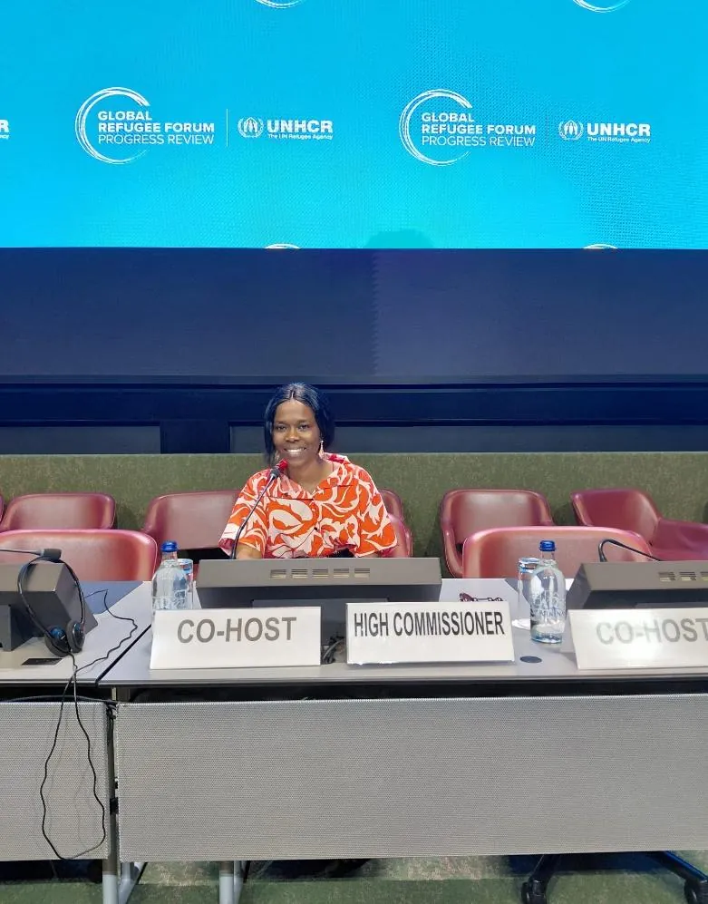 A delegate seated at the co-host table of the Global Refugee Forum Progress Review, under the UNHCR banner