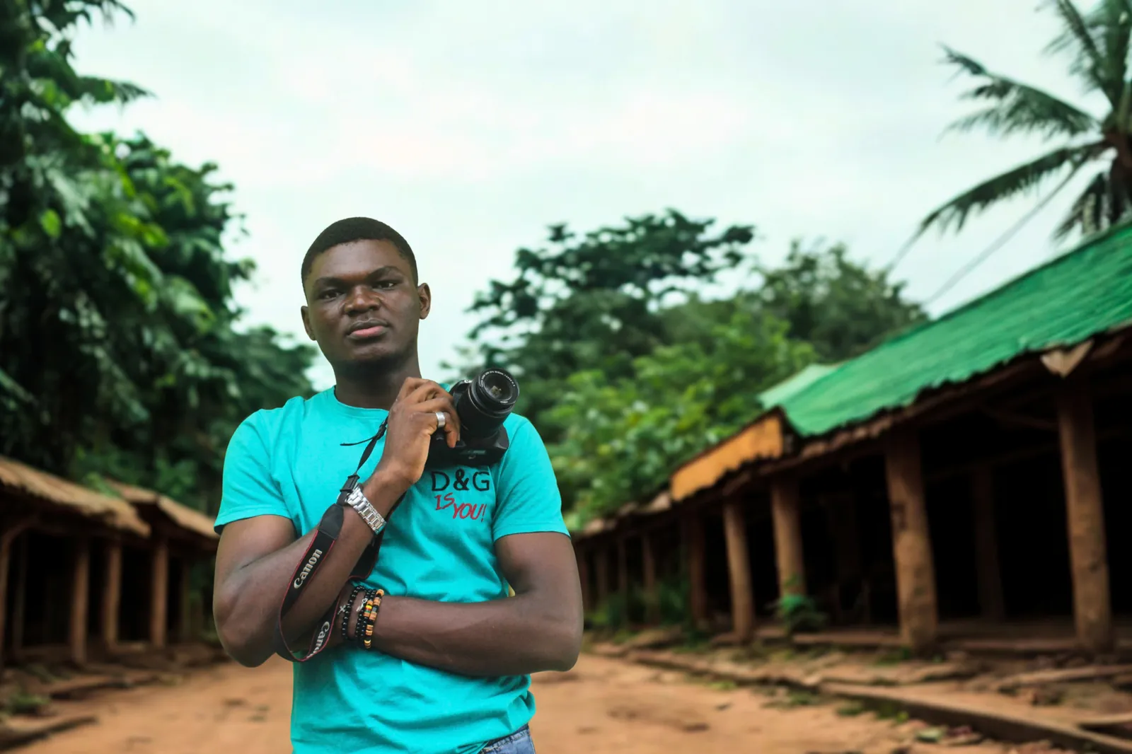 Preston, a former Lens on Life learner, standing with his camera on a village street